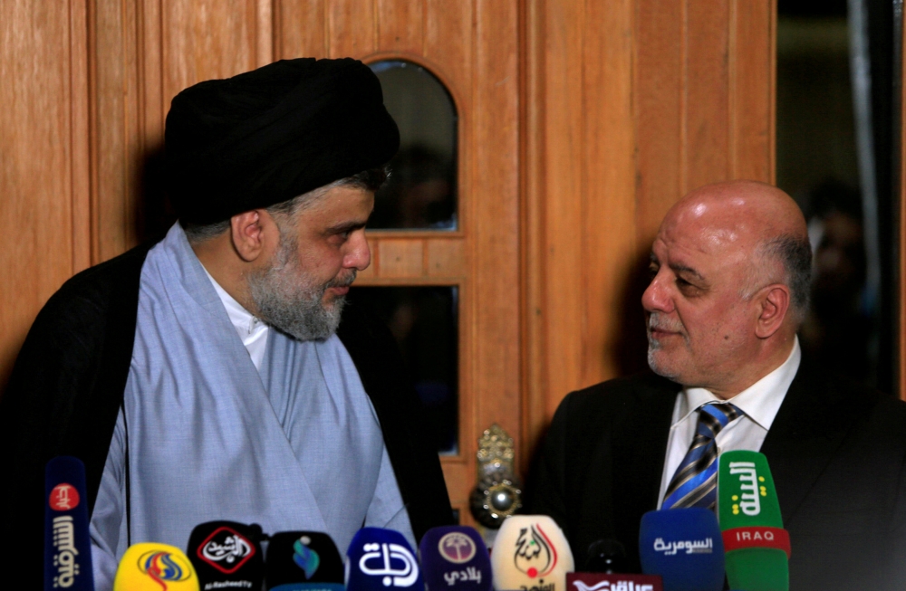 FILE PHOTO: Iraqi cleric Moqtada al-Sadr looks at Prime Minister Haider al-Abadi during a news conference in Najaf, June 23, 2018. (Reuters/Alaa al-Marjani) 