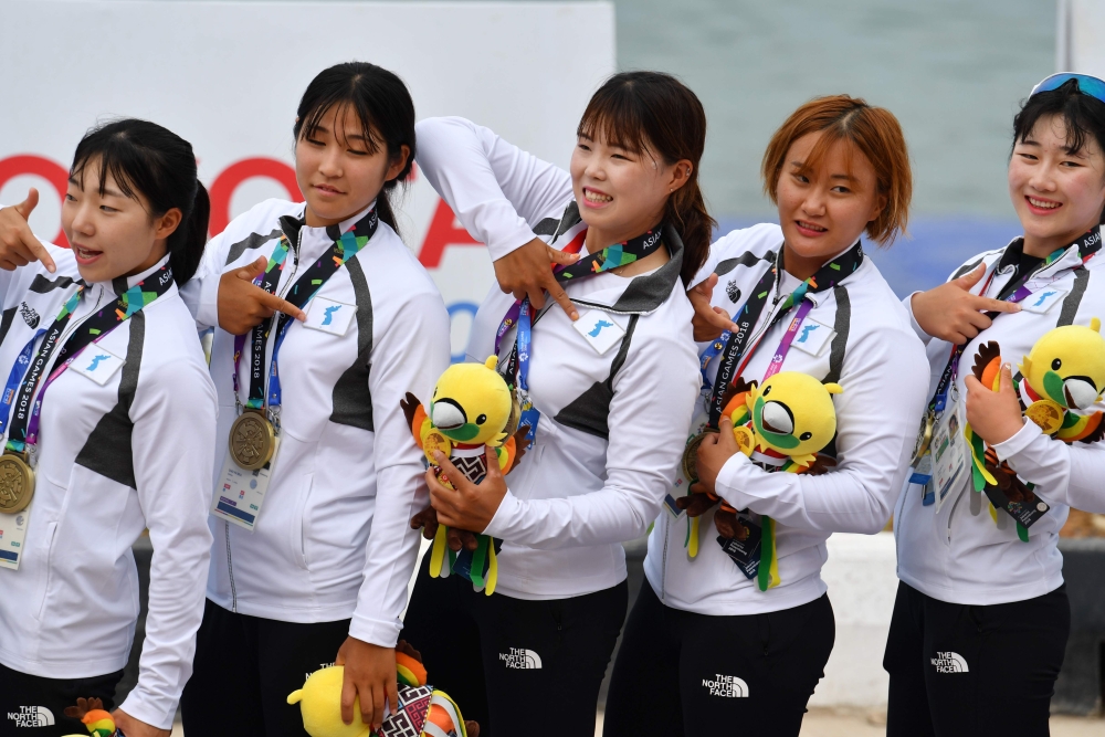 Members of the Unified Korea team pose on the podium after receiving their bronze medals during a medal ceremony for the women's canoe 200m traditional boat race at the 2018 Asian Games in Palembang on August 25, 2018. (AFP / ADEK BERRY)