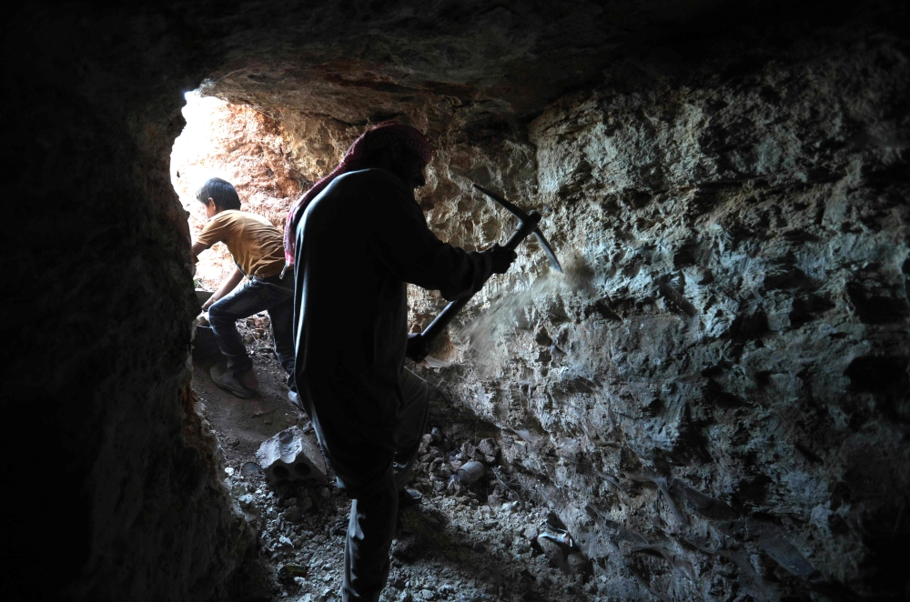A man uses a pickaxe to dig a cave in the Syrian village of Kafr Ain in the southern countryside of the rebel-held Idlib province on September 15, 2018. AFP / OMAR HAJ KADOUR