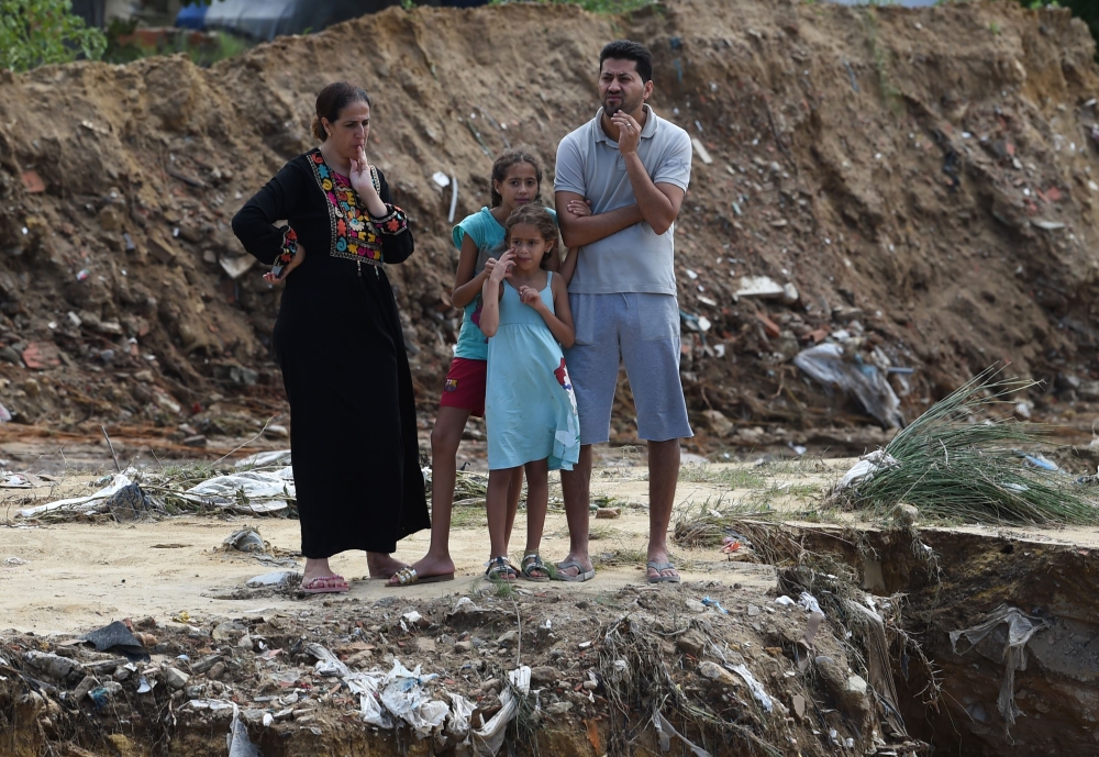 Tunisians look at the damage at the site of a collapsed bridge in the Tunisian coastal governorate of Nabeul on September 23, 2018 following deadly flash flooding in the town of Bir Challouf.  AFP / Fethi Belaid 
