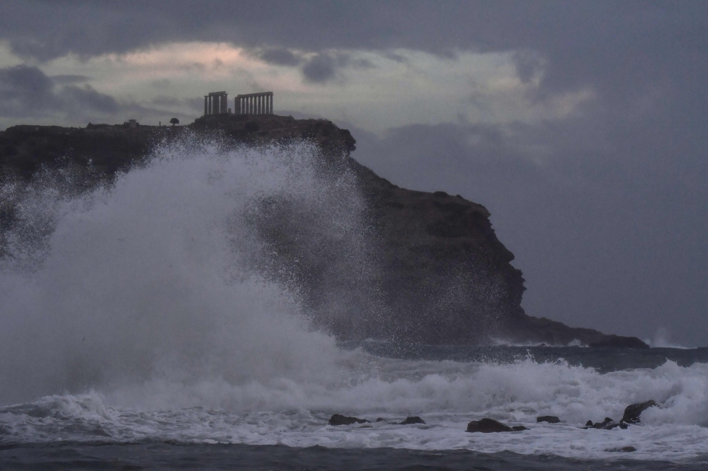 Waves hit the cliffs in front of the ancient Temple of Poseidon at cape Sounion, in southern Athens during bad weather on September 29, 2018. / AFP / Aris MESSINIS