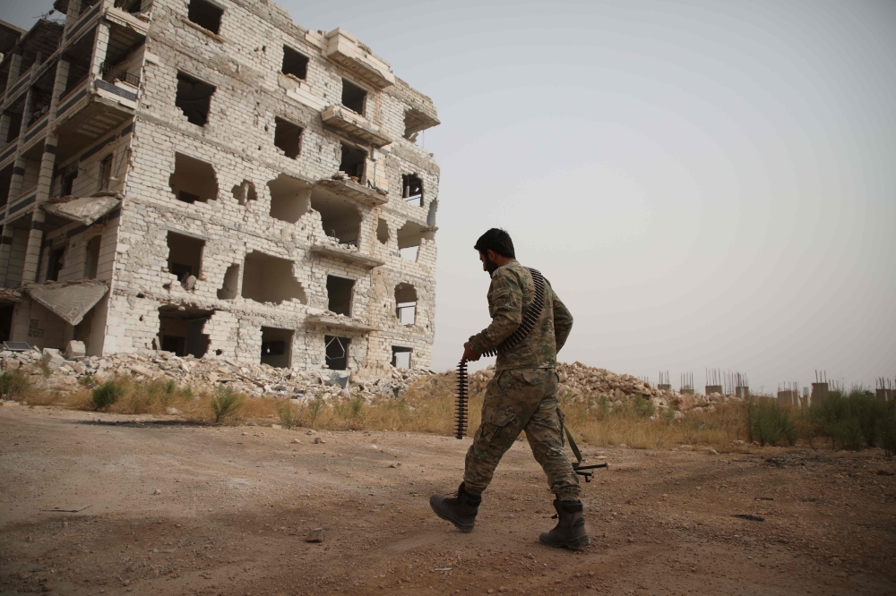 A Syrian rebel-fighter from the National Liberation Front (NLF) walks in a street in the rebel-held al-Rashidin district of western Aleppo's countryside near Idlib province, on October 15, 2018.   AFP / Aaref WATAD