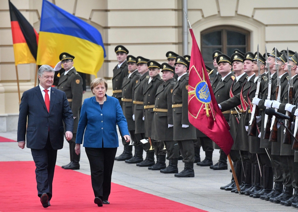 Ukrainian President Petro Poroshenko (L) and German Chancellor Angela Merkel speak as they walk in front of a guard of honour during a welcoming ceremony before their meeting in Kiev on November 1, 2018. / AFP / GENYA SAVILOV