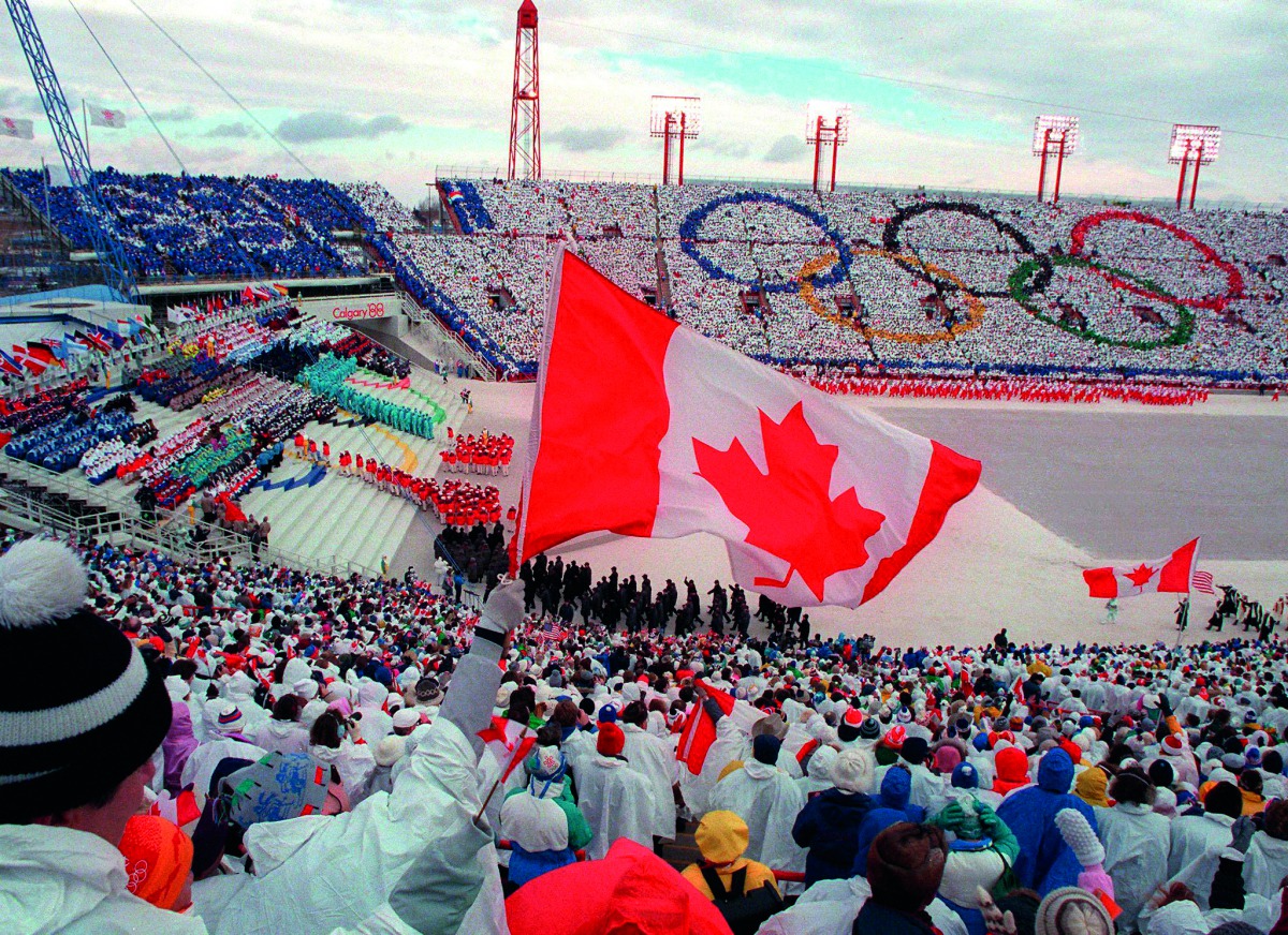 In this file photo taken on February 13, 1988 fans cheer and wave flags as the Canadian delegation (lower right) parades during the opening ceremony of the XVth Winter Olympic Games in Calgary. AFP / Jonathan Utz