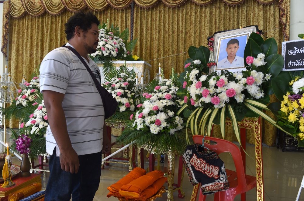 Boxing coach Somsak Deerujijaroen looks at a portrait of thirteen-year-old Muay Thai boxer Anucha Tasako during is funeral at a Buddhist temple in Samut Prakan province on November 14, 2018. AFP / Romeo GACAD