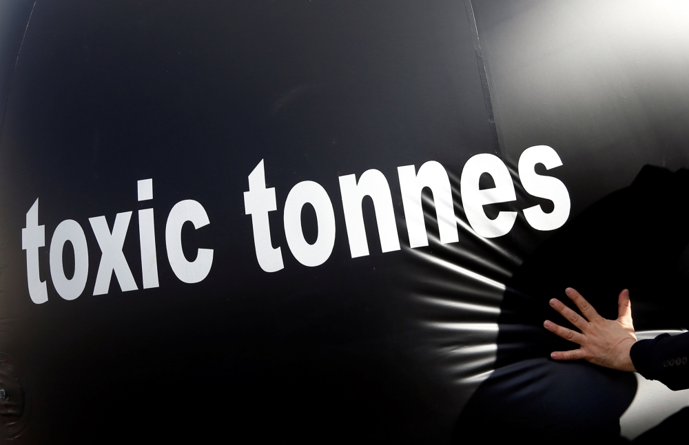 An environmental activist pushes a giant ball with the words, 