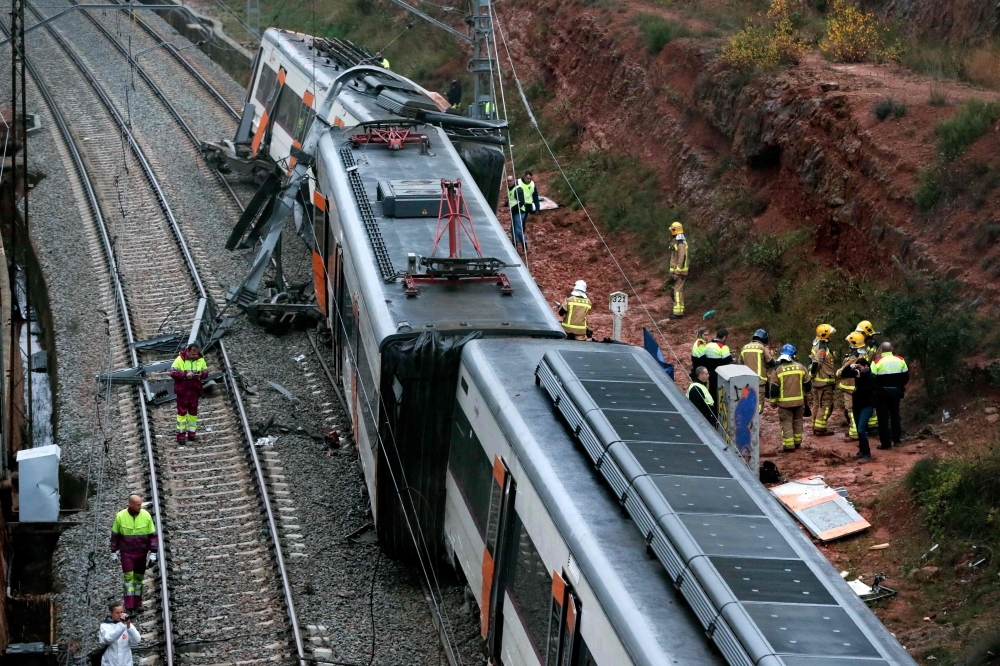 Emergency personnel stand at the site where a commuter train derailed in the town of Vacarisses, about 35 kilometres (20 miles) northeast of Barcelona, on November 20, 2018. AFP / Pau Barrena