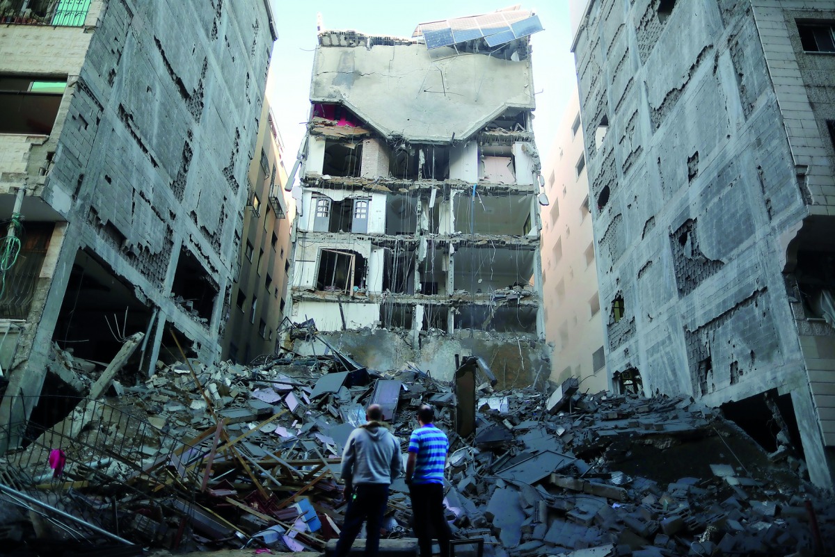 Palestinians stand near the rubble of a building that was completely destroyed by an Israeli air strike, in Gaza City on November 13.