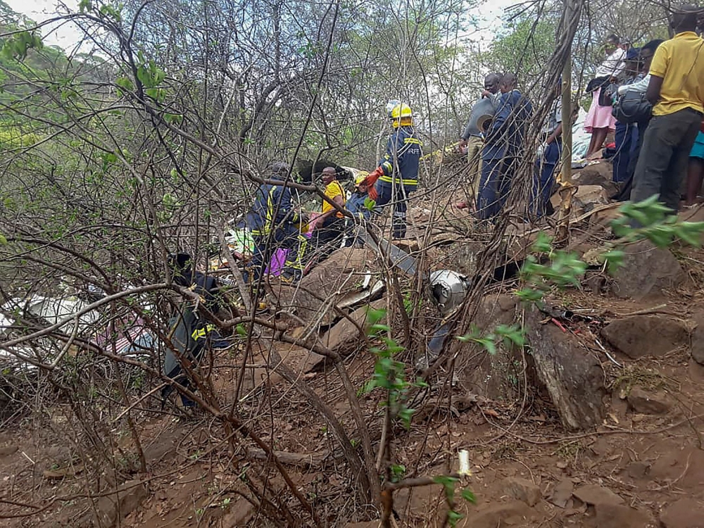 In this photograph taken with a mobile phone, Zimbabwe Rescue Services members look and search through the debris of a crashed light aircraft at Ngundu in Masvingo on November 23, 2018.   AFP / Bekithemba Dube
