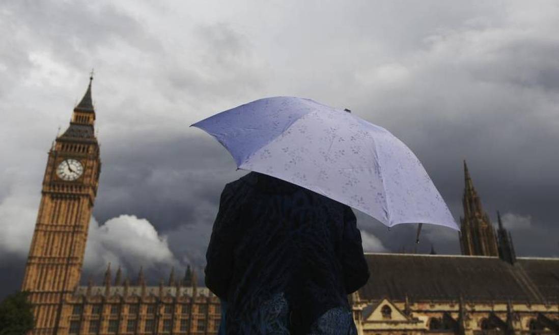 A woman looks towards dark clouds over the Houses of Parliament in central London, August 11, 2014. Reuters/Luke MacGregor
