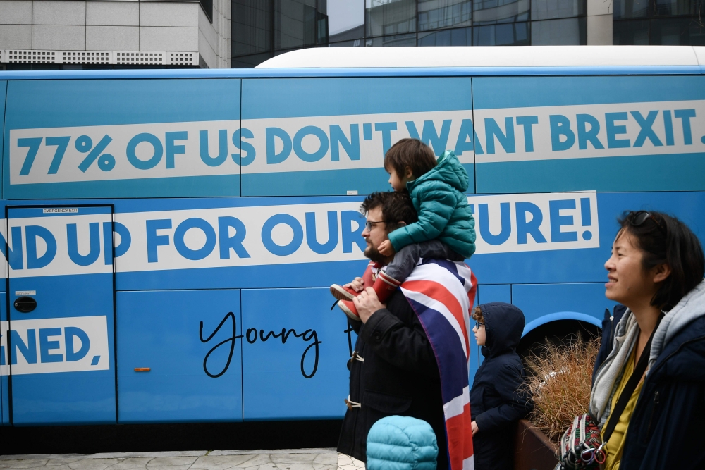 A man wearing a UK flag stands by a bus during a protest against Brexit outside the EU Headquarters in Brussels on November 25, 2018, in Brussels, as occurs a special meeting of the European Council to endorse the draft Brexit withdrawal agreement and to 