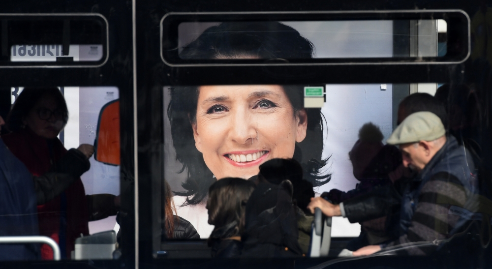 Commuters travel in a bus past an election poster of presidential candidate Salome Zurabishvili in Tbilisi on November 27, 2018, on the eve of the second round of presidential elections. / AFP / Vano Shlamov 
