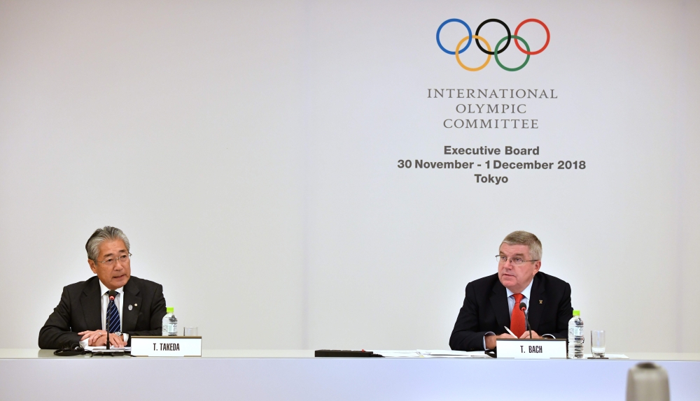 Tsunekazu Takeda (L), President of the Japanese Olympic Committee, delivers a speech while International Olympic Committee (IOC) President Thomas Bach (R) listens at the IOC Executive Board meeting in Tokyo on November 30, 2018. / AFP / Kazuhiro NOGI 