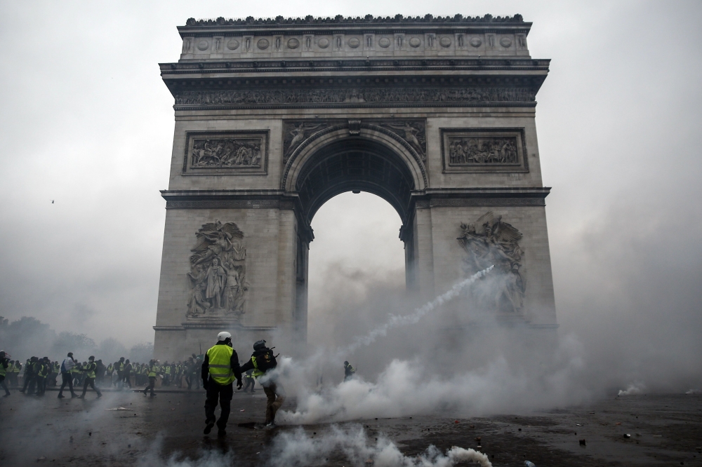  Demonstrators clash with riot police at the Arc de Triomphe during a protest of Yellow vests (Gilets jaunes) against rising oil prices and living costs, on December 1, 2018 in Paris. / AFP / Abdulmonam EASSA