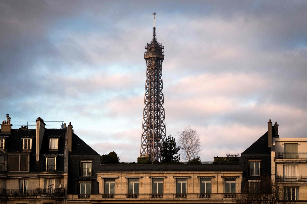 The top of the Eiffel Tower peeks out above the roofs on December 4, 2018 in Paris. AFP / Lionel Bonaventure