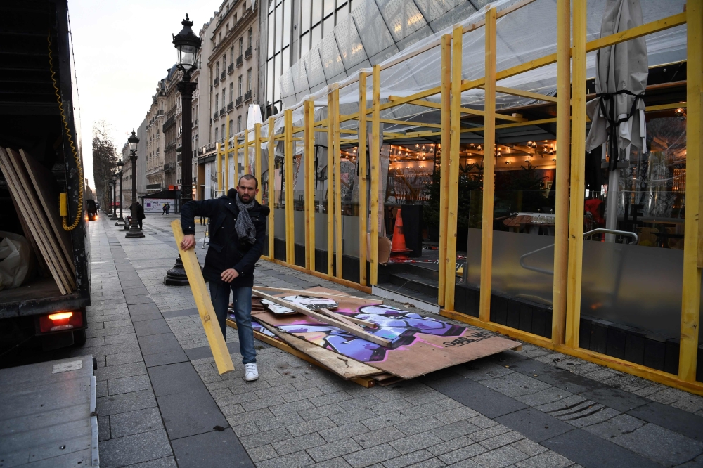 Workers remove wooden wall to protect the drugstore publicis shop near the Arc de Triomphe in Paris, on December 9, 2018 a day after a 