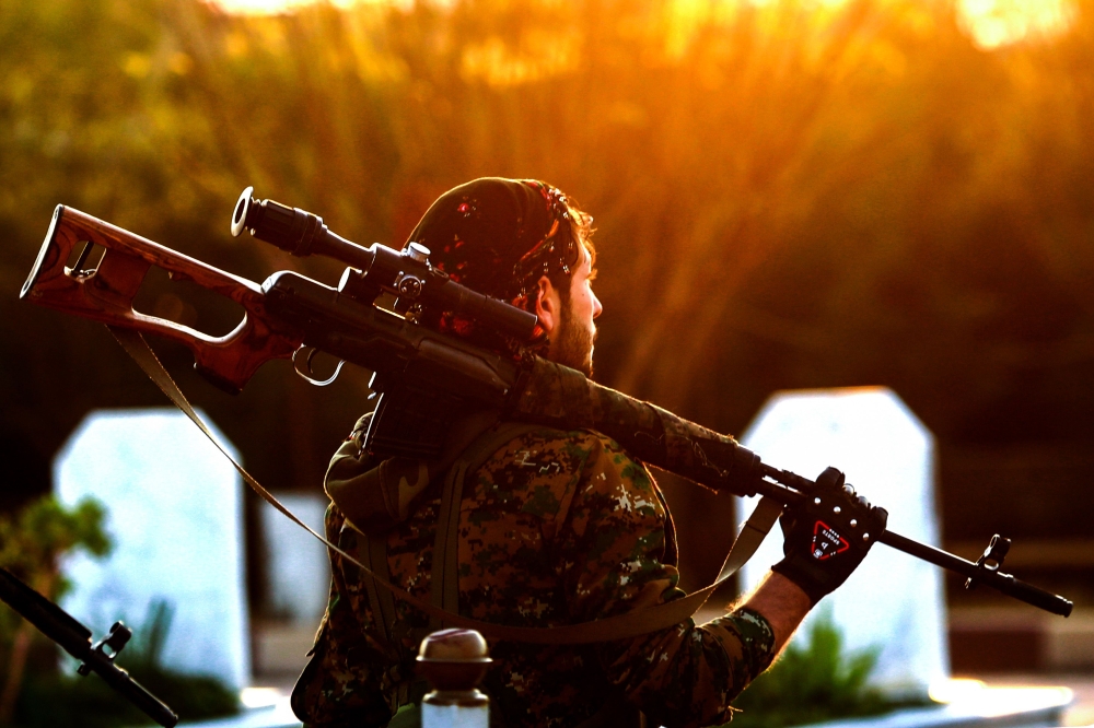 A Syrian Democratic Forces'(SDF) fighter holds a sniper rifle on his shoulder as he attends the funeral of a slain People's Protection Units (YPG) commander in the northeastern city of Qamishli on December 6, 2018. / AFP / Delil SOULEIMAN