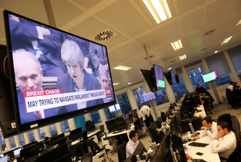 Britain's Prime Minister Theresa May is seen on a large television as traders work at CMC markets in London, Britain, December 11, 2018. REUTERS/Simon Dawson