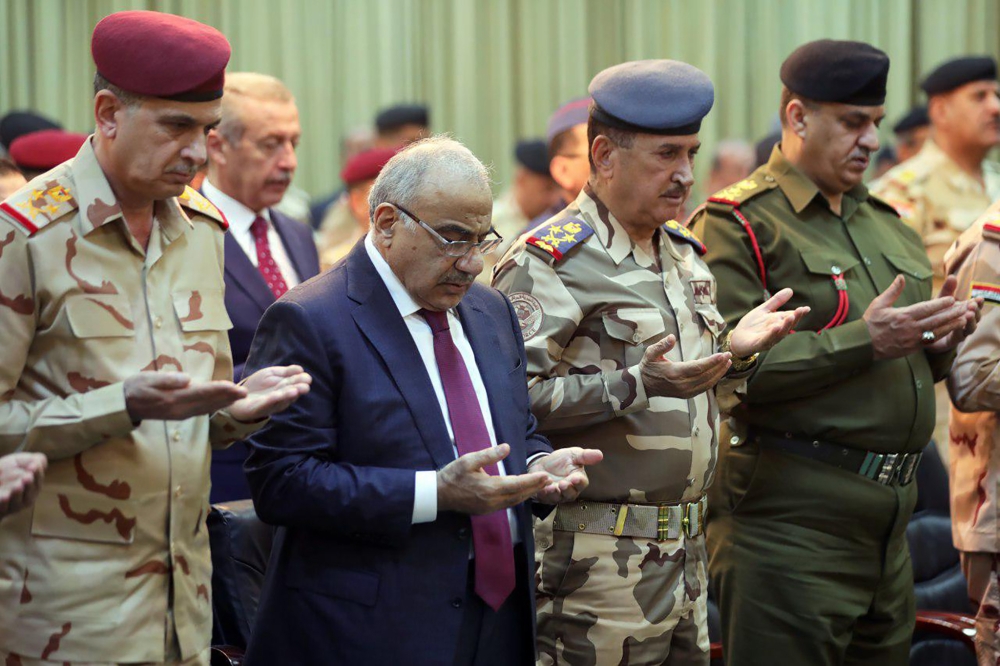 Iraqi PM Adel Abdel Mahdi (2nd-L) praying with military figures during a ceremony held in the capital Baghdad, on the first anniversary of the country's victory over the Islamic State (IS) group on December 10, 2018.  AFP photo/ Iraqi Prime Minister's Off