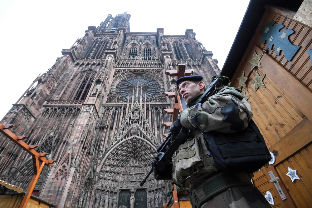 French soldiers stand guard at the Christmas market in front of the Cathedral, on December 12, 2018, as policemen conduct a search in order to find the gunman who opened fire near a Christmas market the night before, in Strasbourg, eastern France. AFP / P