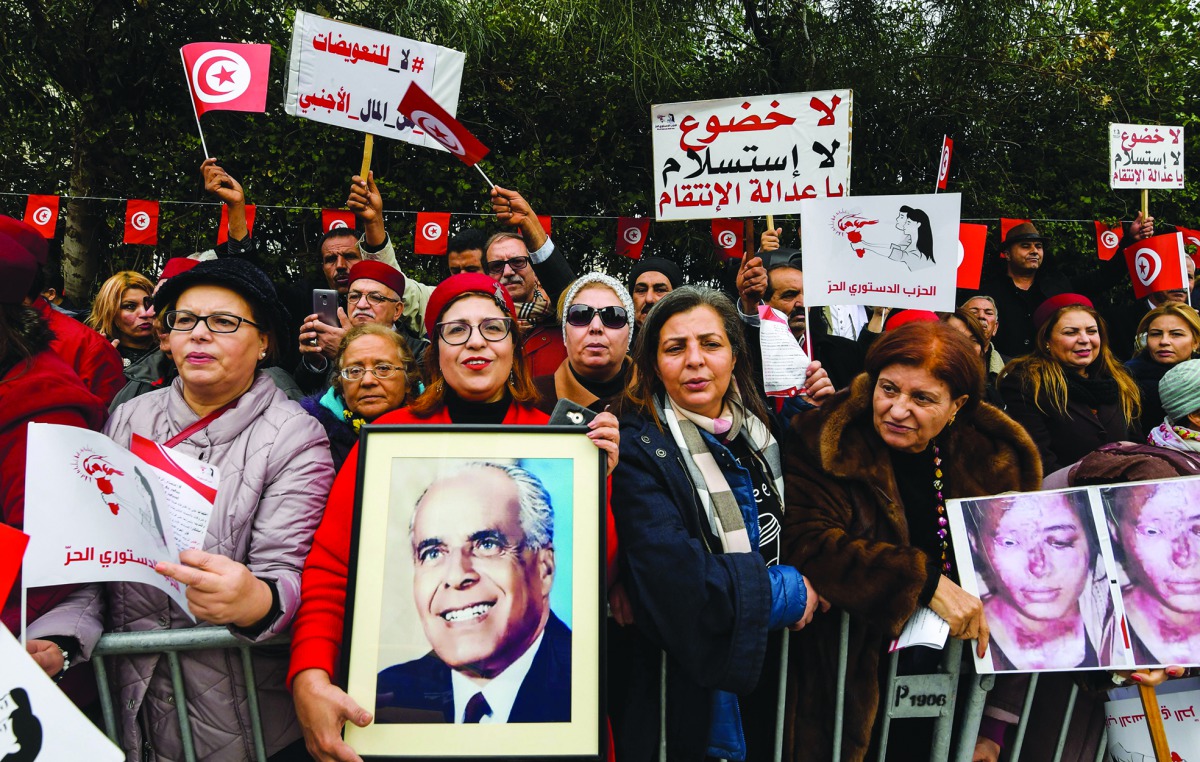 Members of Tunisia's Free Destourian Party (Free Constitutional Party) shout slogans and hold up protest signs and portraits of late president Habib Bourguiba as they demonstrate against the Truth and Dignity Commission (TDC) outside its closing conferenc