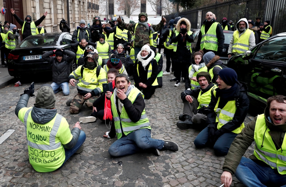 Protesters wearing yellow vests sit on the floor during a demonstration by the 