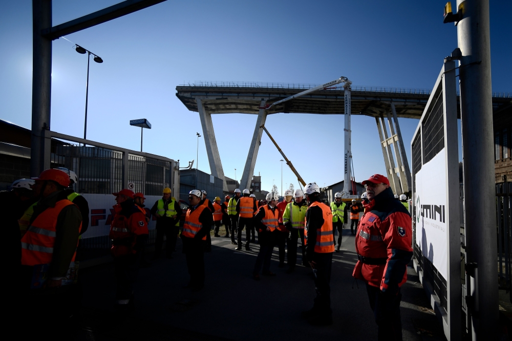 Workers and officials gather by remains of the Morandi Bridge for a preleminary meeting in Genoa on December 15, 2018.  AFP / Filippo MONTEFORTE