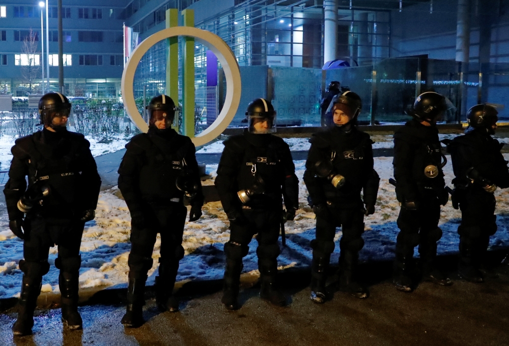 Police forces stand guard outside the headquarters of the Hungarian state television during a protest against a proposed new labor law, billed as the 