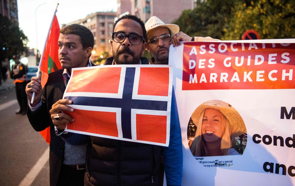 Moroccan tour guides hold up flags of Norway and Morocco as they gather to pay tribute to the two murdered Scandinavian hikers in the central city of Marrakesh on December 21, 2018.   AFP / FADEL SENNA