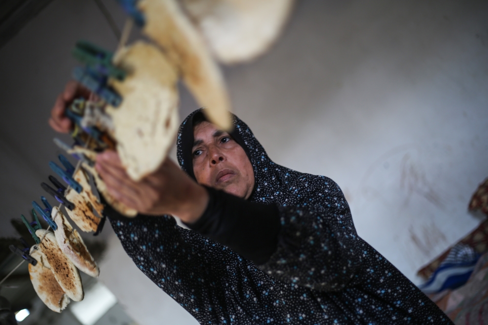  Gazan woman Fairouz attaches a bread on a rope with a clothespin in Gaza City, Gaza on December 12, 2018. ( Mustafa Hassona - Anadolu )	