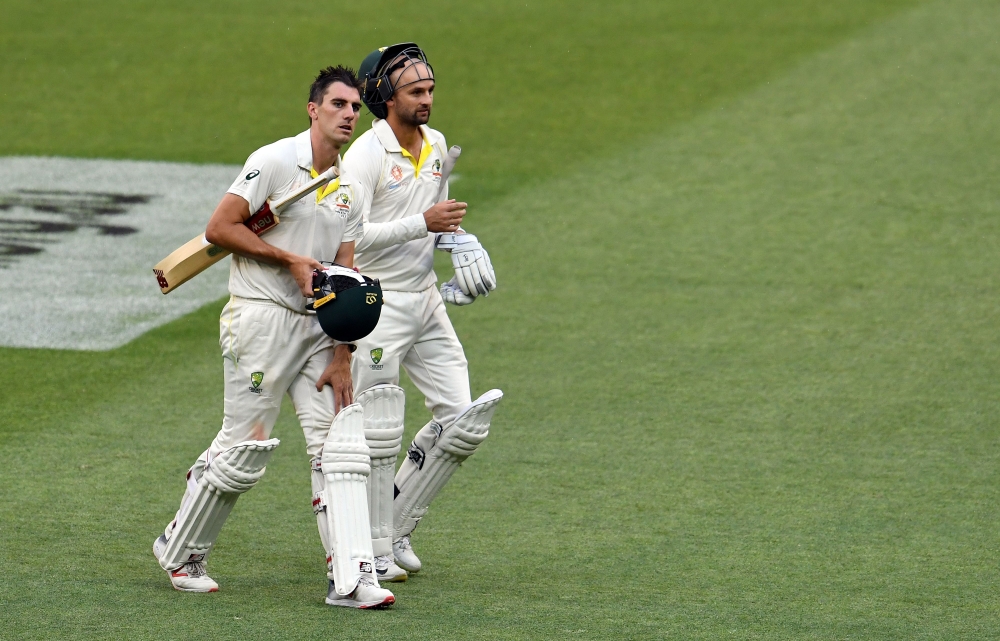 Australia's unbeaten batting pair Pat Cummins (L) and Nathan Lyon walk back to the pavilion at the end of fourth day's play of the third cricket Test match between Australia and India in Melbourne on December 29, 2018. AFP / WILLIAM WEST /