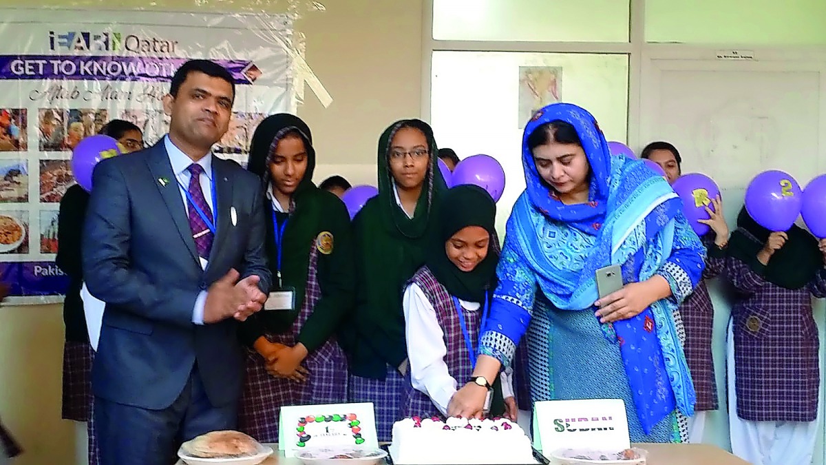 School officials with Sudanese students cutting a cake.