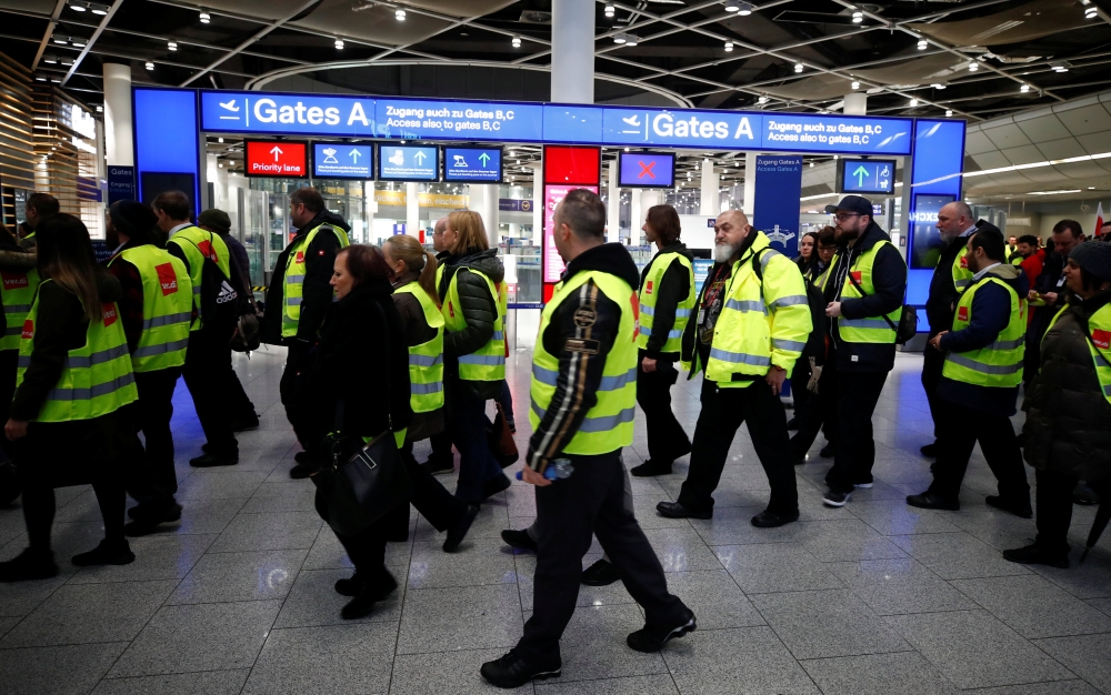 Members of Germany's union Verdi wear yellow vests as they march in front of Gate A of Duesseldorf Airport during a strike by Verdi, which called on security staff at Duesseldorf, Cologne and Stuttgart airports to put pressure on management in wage talks,