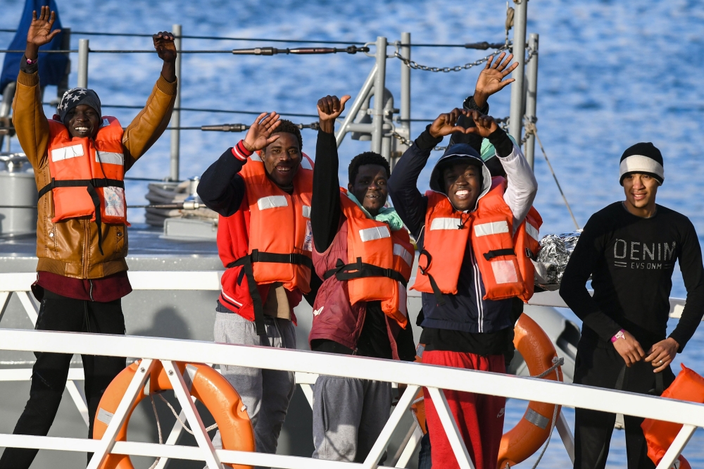 Migrants, part of a group of 49, wave towards the media as they disembark from one of Malta's AFM Protector-class coastal patrol boats on January 9, 2019 after being transfered from the Dutch-flagged rescue Vessel 