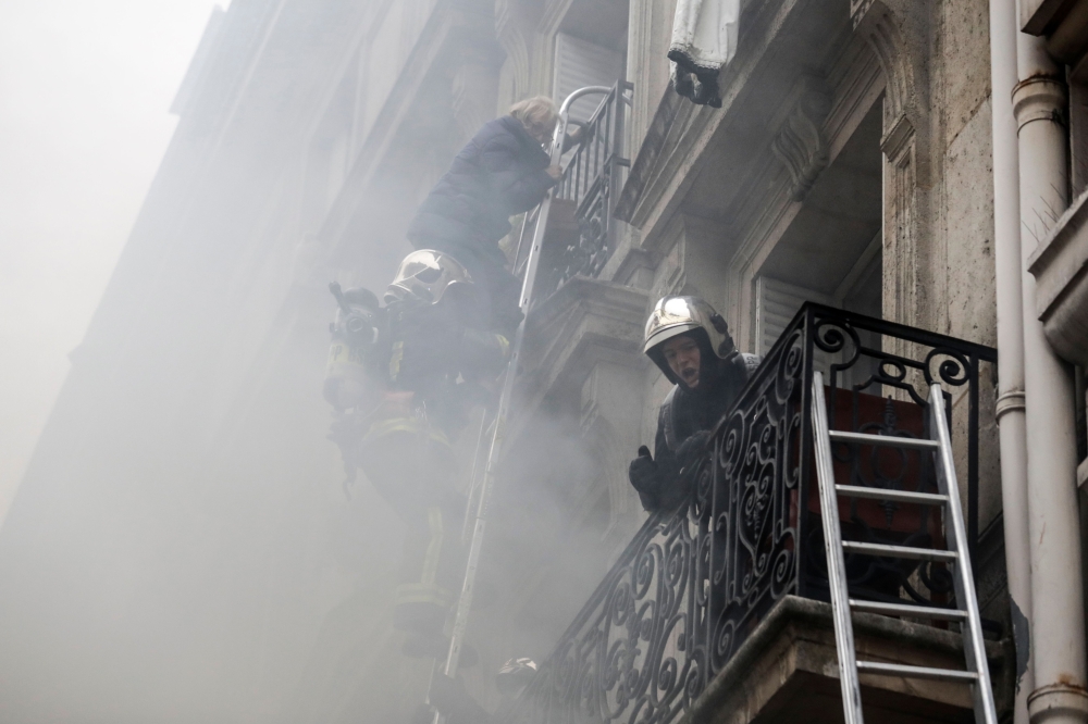A person is evacuated by firefighters from an apartment after the explosion of a bakery on the corner of the streets Saint-Cecile and Rue de Trevise in central Paris on January 12, 2019.   AFP / Thomas SAMSON