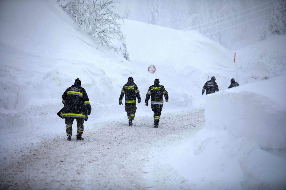 Firefighters walk at the valley station of the Hochkar cable car at 1380 m altitude on January 13, 2019 in Hochkar.  / ALEX HALADA / AFP