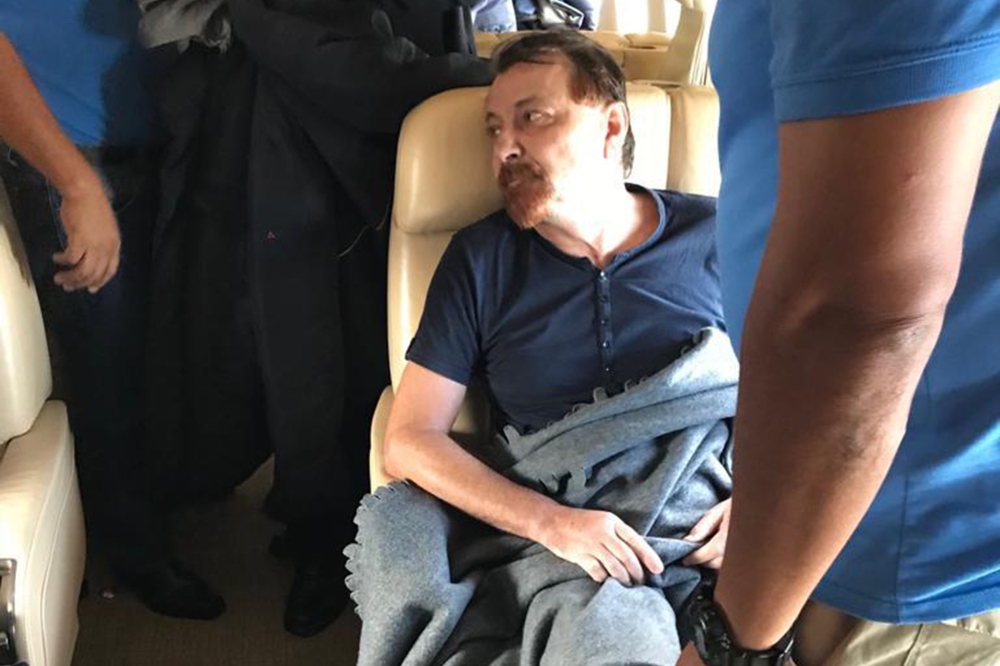 A picture handout by the Italian Interior Ministry clicked and released by the Polizia di Stato on January 13, 2019, shows former far-left Italian militant Cesare Battisti sitting aboard a plane chartered by the Italian government, prior to taking off fro