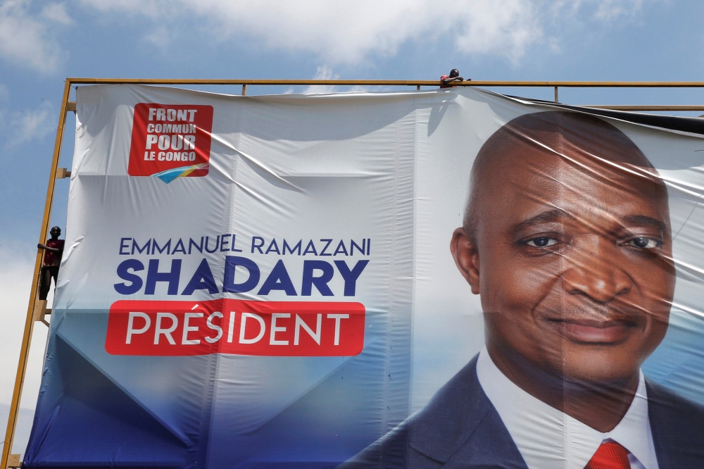 Men remove an electoral campaign banner of Emmanuel Ramazani Shadary, former Congolese interior minister and presidential candidate, in Kinshasa, Democratic Republic of Congo, January 2, 2019. Reuters/Baz Ratner
