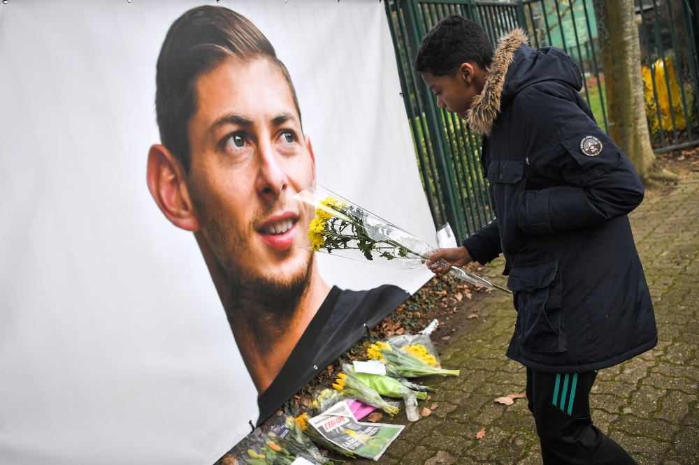 A young man brings flowers in front of the entrance of the FC Nantes football club training center La Joneliere in La Chapelle-sur-Erdre on January 23, 2019, two days after the plane of Argentinian forward vanished during a flight from Nantes in western F
