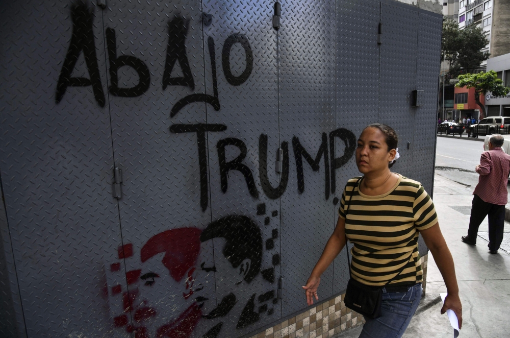 A woman walks past a grafitti depicting late Venezuelan president Hugo Chavez (R), President Nicolas Maduro and a legend reading 