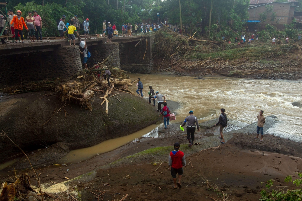 This picture taken on January 25, 2019 shows Indonesian rescuers repairing a bridge after a landslide in Gowa, after heavy rains and strong winds pounded the southern part of Sulawesi island. Floods and landslides in Indonesia have killed at least 59 peop