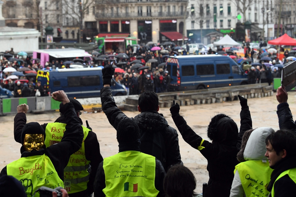 People wearing Yellow vests gestures as French 'red scarves' (foulards rouges), critics of violent 'yellow vest' (Gilets Jaunes) protest in Paris on January 27, 2019. AFP / Alain Jocard 