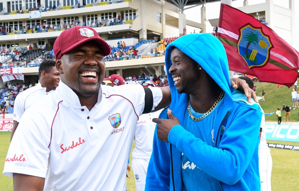 Darren Bravo (L) and Kemar Roach (R) of West Indies celebrate winning on day 3 of the 2nd Test between West Indies and England at Vivian Richards Cricket Stadium in North Sound, Antigua and Barbuda, on February 02, 2019. / AFP / Randy Brooks 