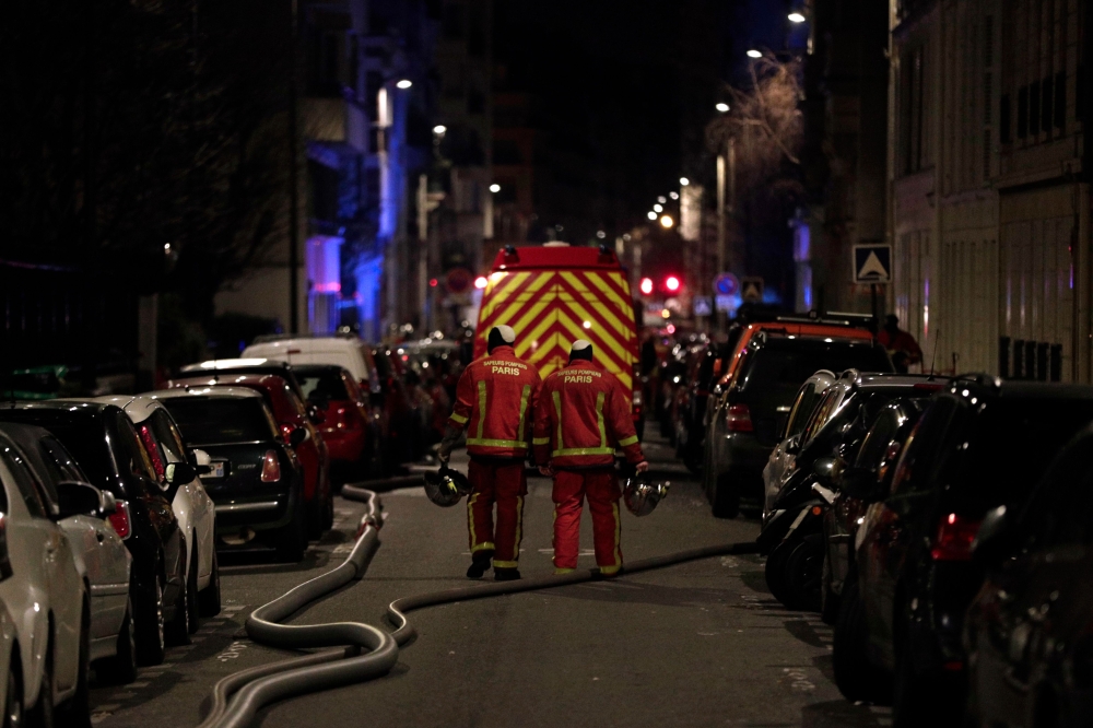 Firefighters are seen near a building that caught fire in the 16th arrondissement in Paris, on February 5, 2019. AFP / Geoffroy VAN DER HASSELT