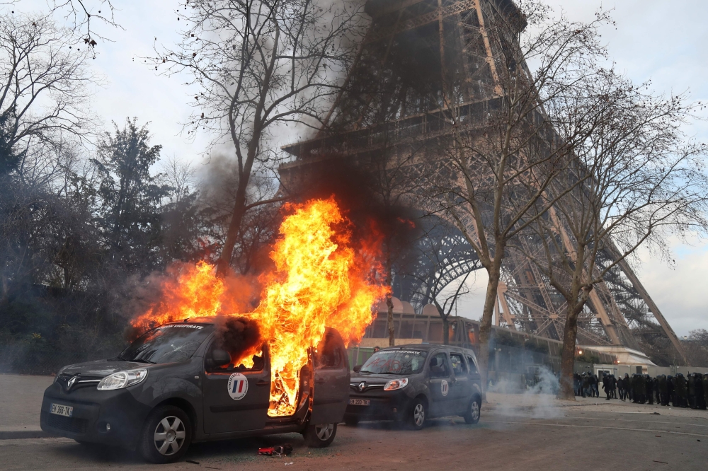 A Sentinelle security operation car burns in front of the Eiffel Tower, on the sidelines of a demonstration in Paris on February 9, 2019, as the 