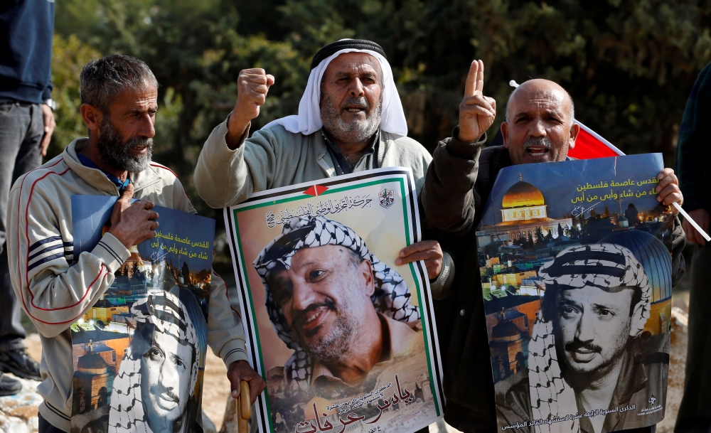 FILE PHOTO: Demonstrators hold posters depicting Yasser Arafat during a rally marking the 14th anniversary of his death near Hebron in the occupied West Bank, November 11, 2018. Reuters/Mussa Qawasma