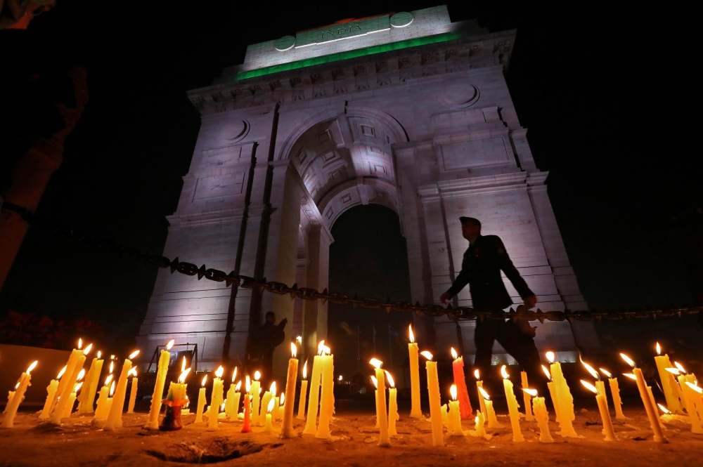 A soldier walks during a candle light vigil to pay tribute to Central Reserve Police Force (CRPF) personnel who were killed after a suicide bomber rammed a car into the bus carrying them in south Kashmir on Thursday, in front of India Gate war memorial in