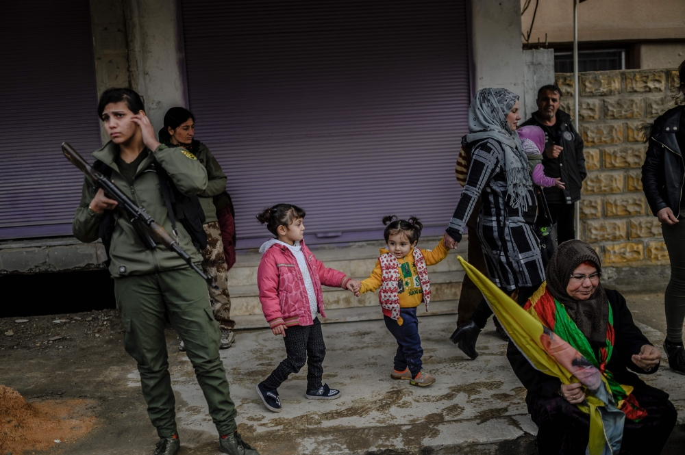 Bystanders and fighters from the Syrian Democratic Forces (SDF) watch a demonstration in support of Kurdish militant leader Abdullah Ocalan, on February 15, 2019, in the northeastern Syrian Kurdish-majority city of Qamishli.  AFP / HECTOR PEREZ