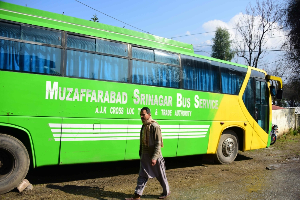 A Pakistani Kashmiri walks past a bus doing the Muzaffarabad-Srinagar Bus Service parked on a street, in Muzaffarabad, the capital of Pakistan's controlled Kashmir on February 19, 2019 following a shut down of the bus service connecting the cities. AFP / 