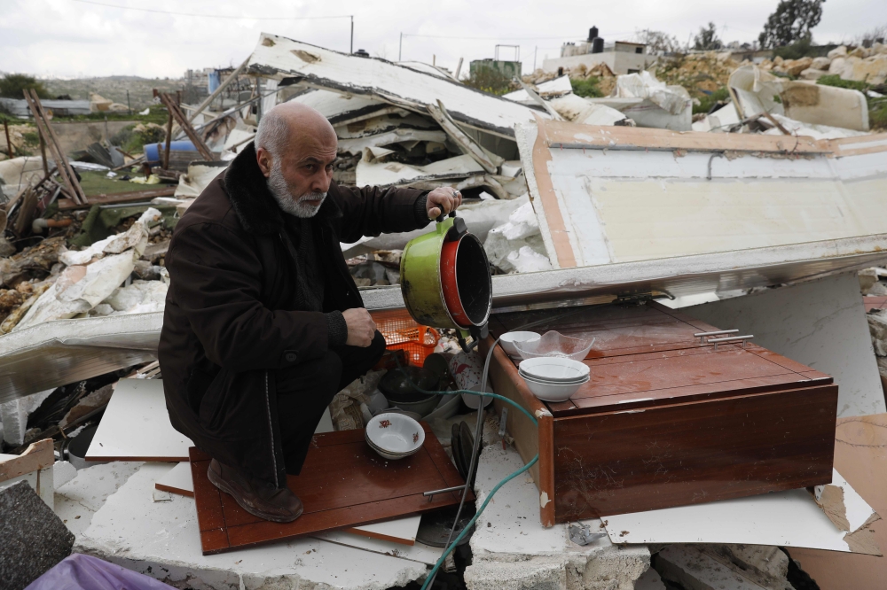 A Palestinian man, salvages some of his belongings from his house that was demolished by Israeli troops in the Arab east Jerusalem neighbourhood of Beit Hanina on February 20, 2019, on the grounds that it was built without a construction permit.  AFP / Ah